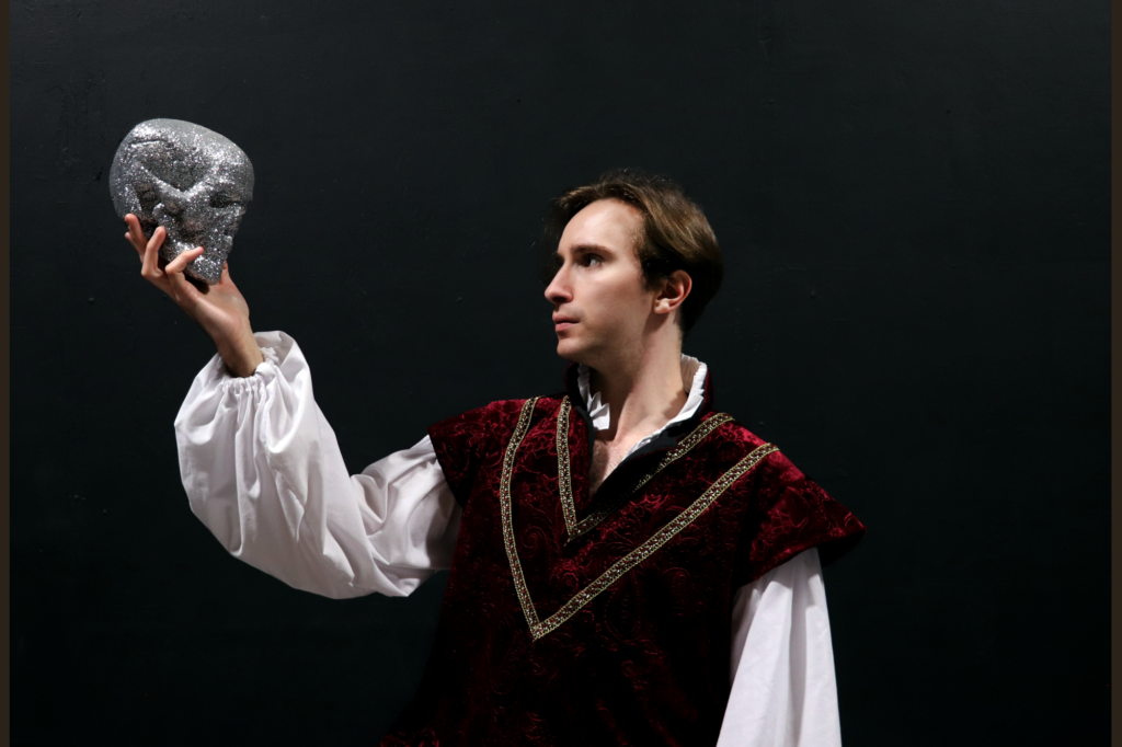 Image of a man dressed as Hamlet holding a skull covered in glitter