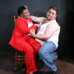 Woman in red suit flirting with man in tank top and jeans.