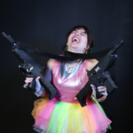 Woman in multicolor neon tutu holding two semiautomatic weapons and laughing